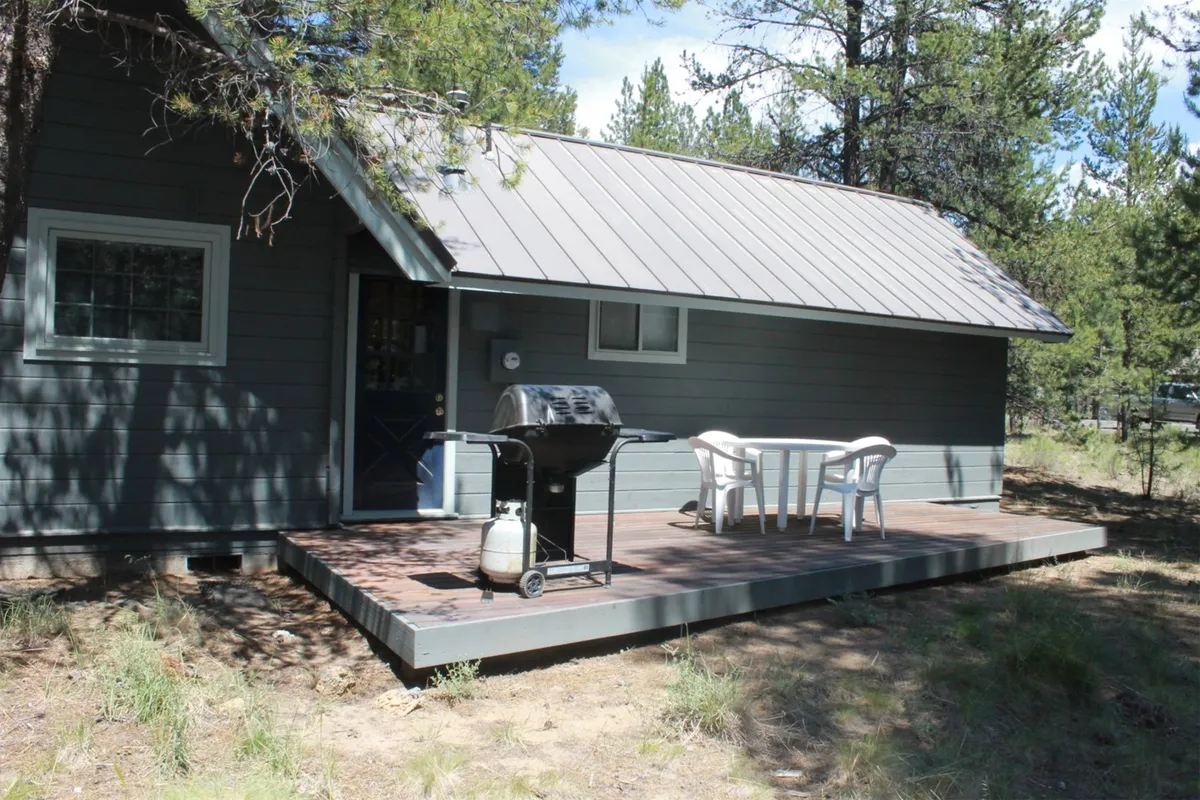 Another angle of the wooden deck, this shot features the grill, outdoor dining table, and the enveloping greenery. It emphasizes the inviting space for barbecues, morning coffee, and evening relaxation.